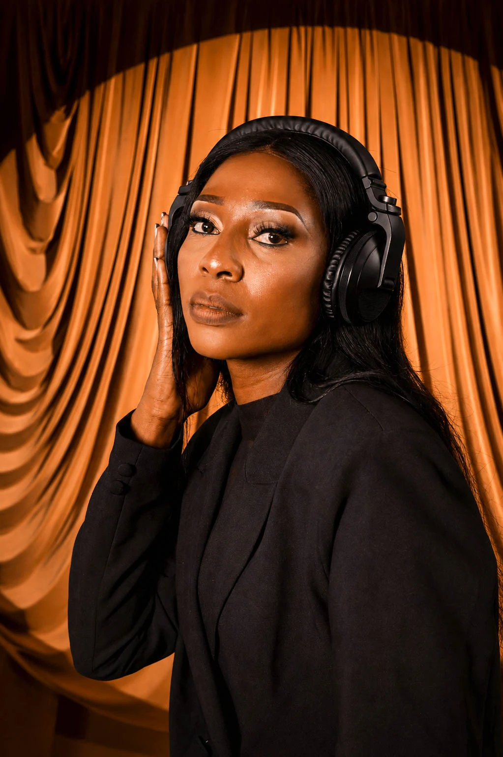 LadyChoc wearing headphones against copper drapes